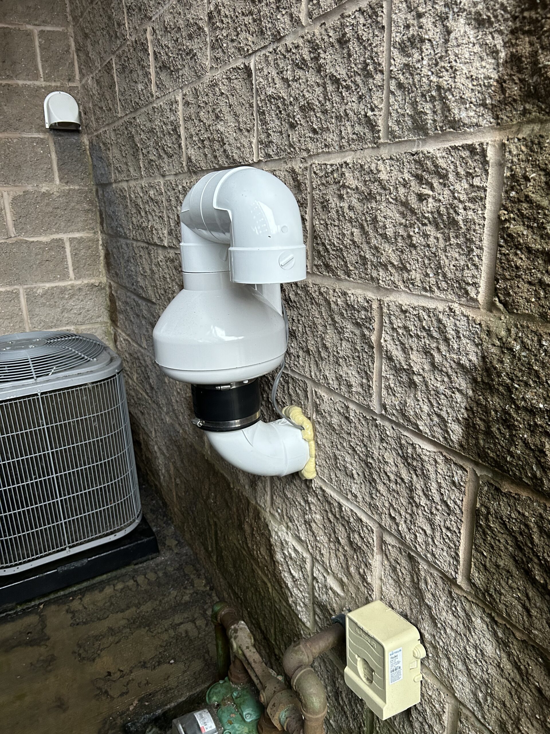 Exterior photo of a ground-level radon exhaust fan