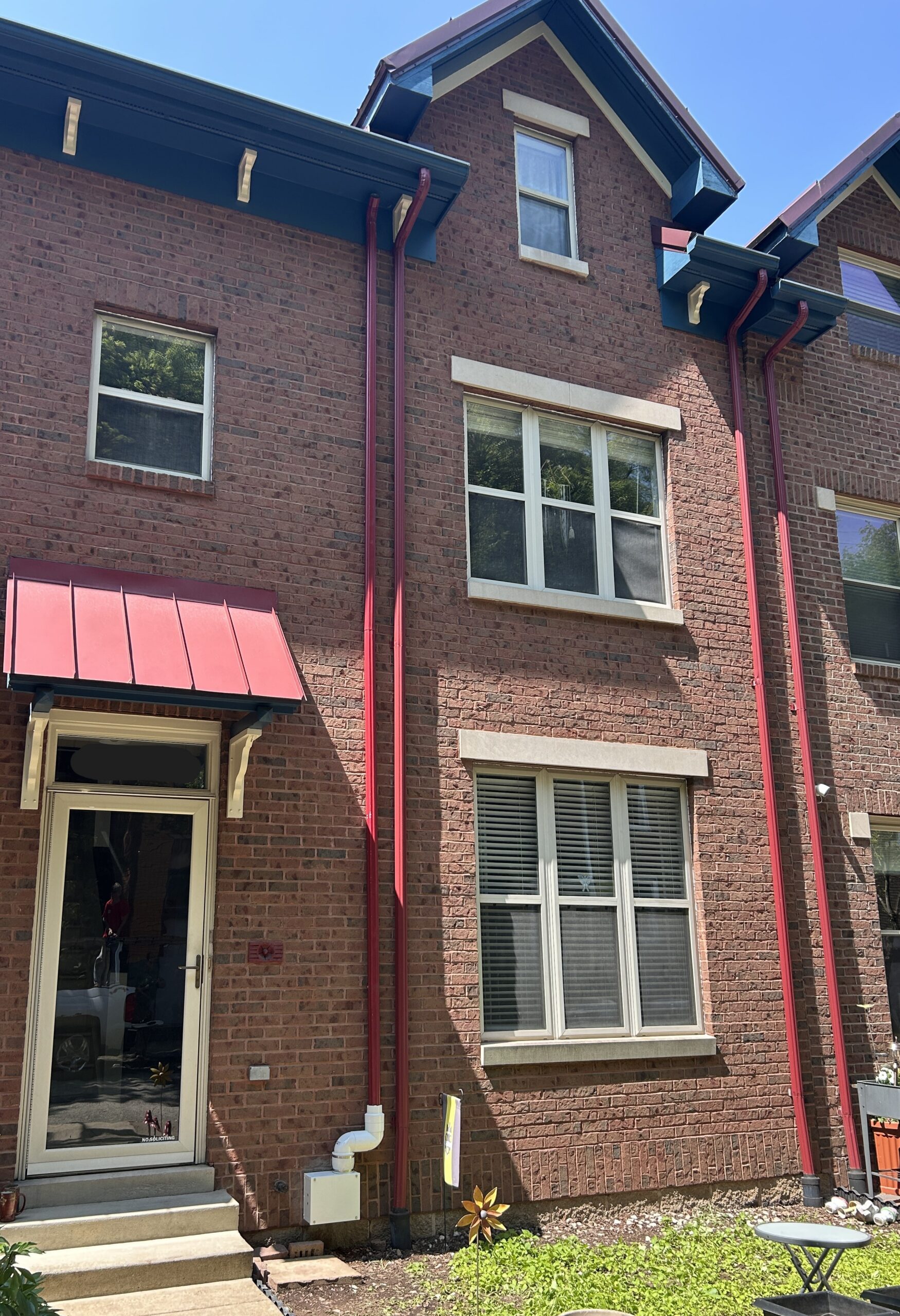 Photo of a newly installed radon mitigation fan on the front of a brick row house.