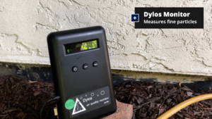 Dylos fine particle monitor resting on a brick beside a stucco wall