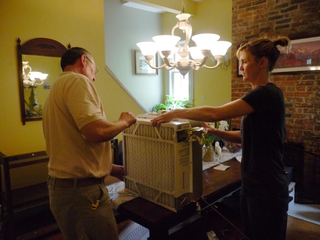 Two adults working together on their DIY fan filter using MERV filters