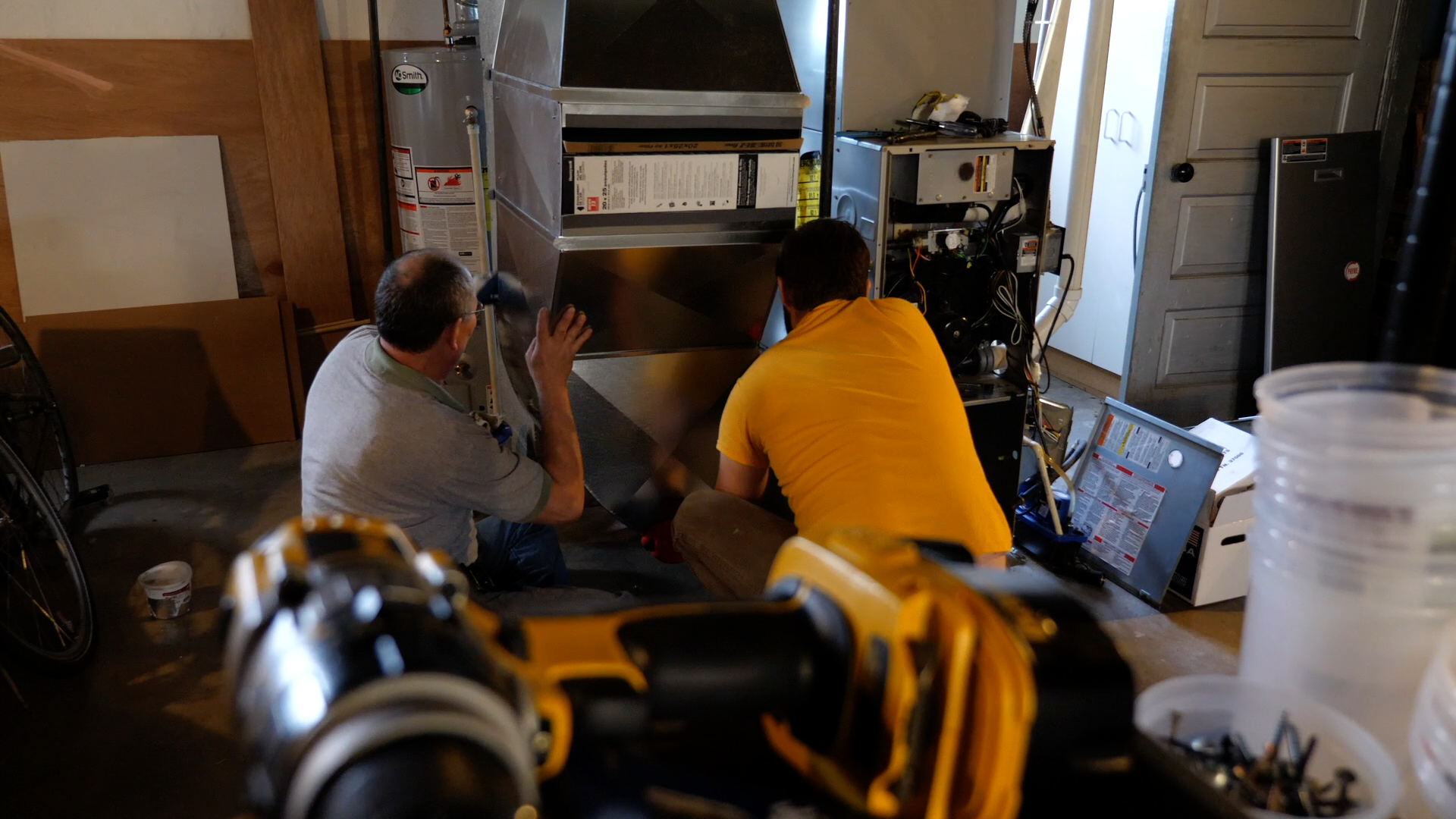 Two men working on an HVAC system in basement
