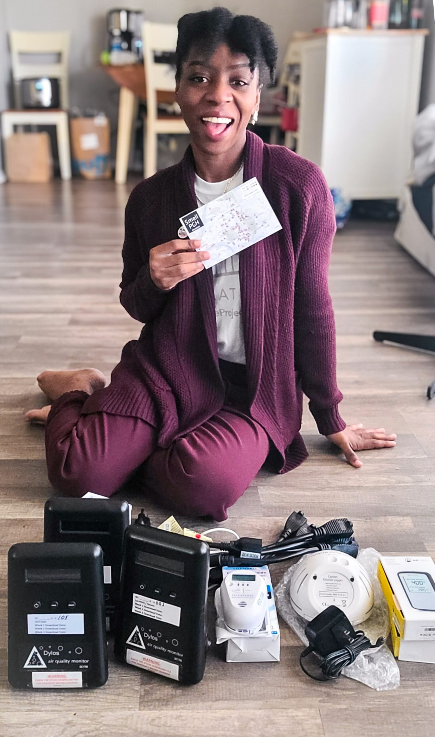 A woman sits on her floor surrounded by air quality monitors