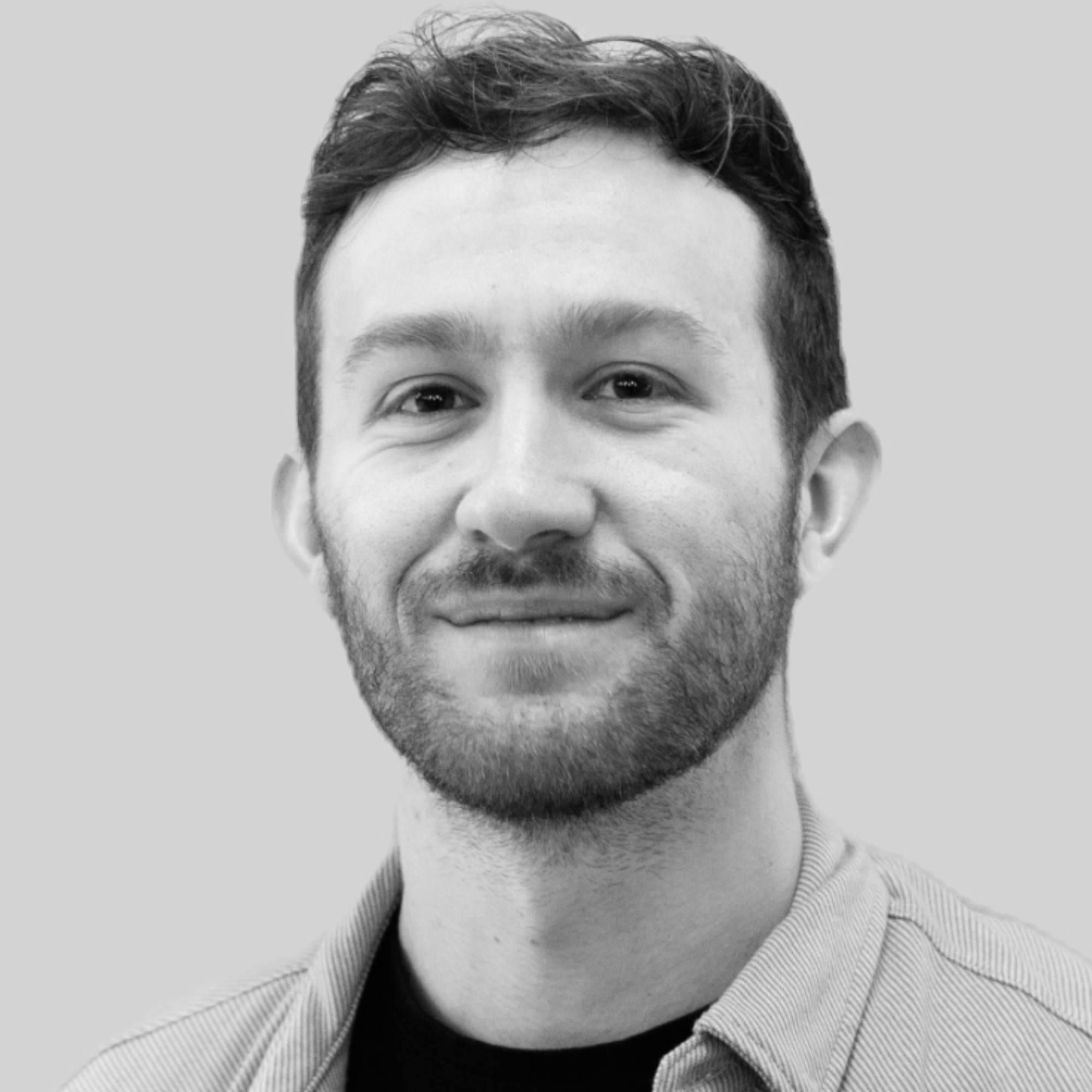 Black and white photo of Matt Oriente, a bearded man smiling at the camera.