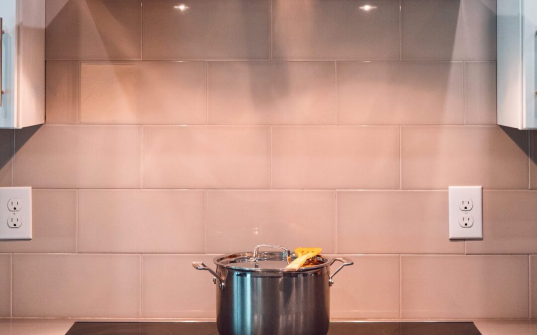 Photo of a kitchen stovetop with a pot on it and a range hood above it.